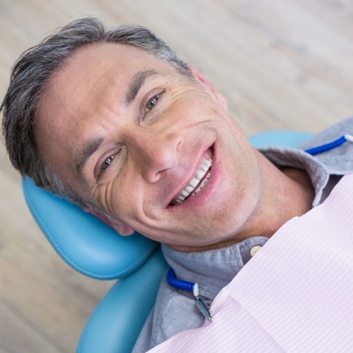 Older man smiling while sitting back in dental chair