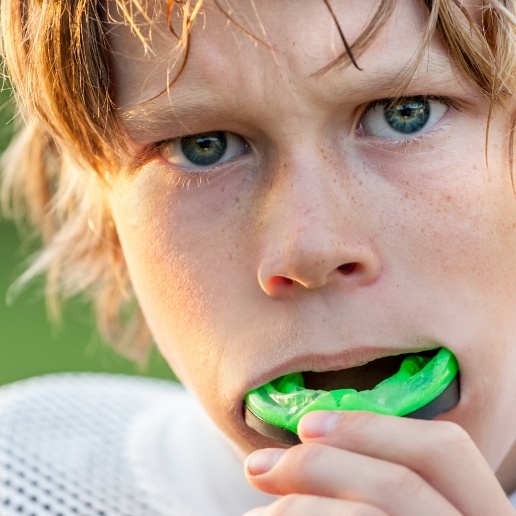 Young boy placing athletic mouthguard over his teeth