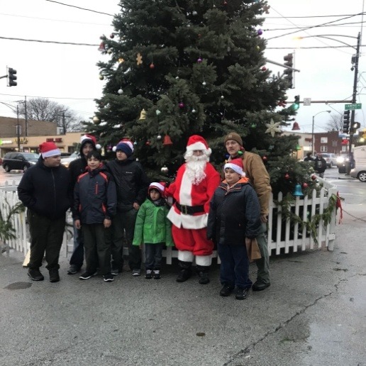 Chicago dentist dressed up as Santa standing in front of Christmas tree on sidewalk