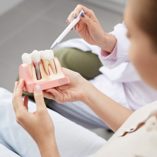 Dentist showing a patient a model of how dental implants work