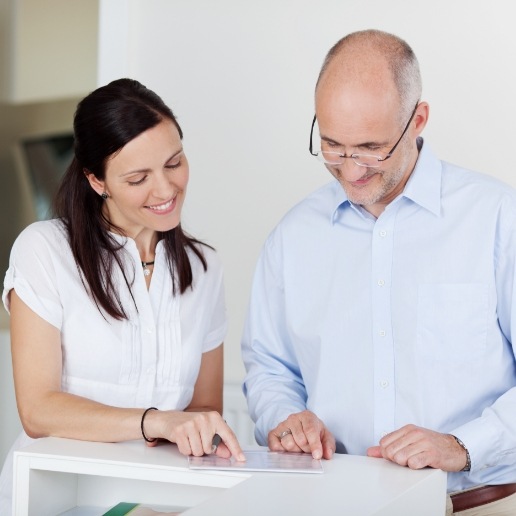 Dental team member looking at paperwork with dental patient