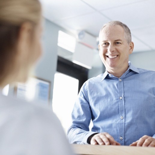 Man talking to dental team member at desk