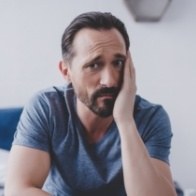 Man in blue shirt holding the side of his face in pain