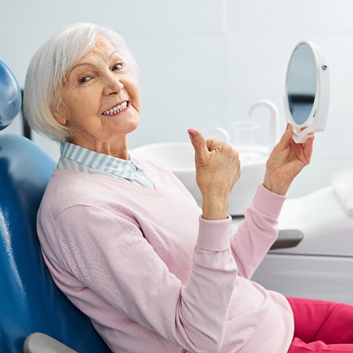 Senior woman sitting in dental chair and giving thumbs up