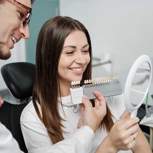 Dentist helping smiling patient choose shade of veneer