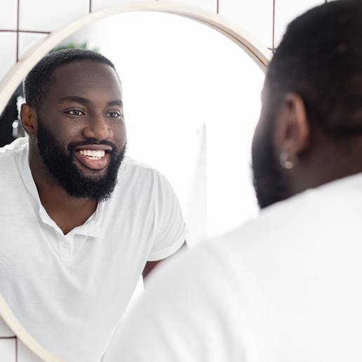 Man smiling at reflection in bathroom mirror