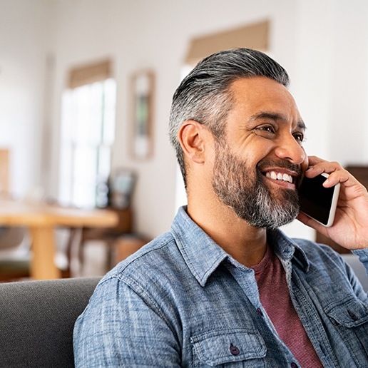 Man smiling while talking on cellphone at home