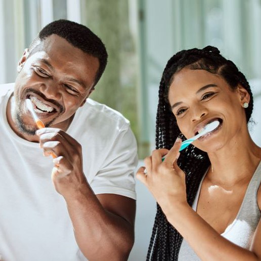 Couple brushing their teeth in front of bathroom mirror